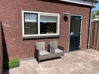 a patio with two chairs and a table in front of a brick building at Landzicht in Ter Aar