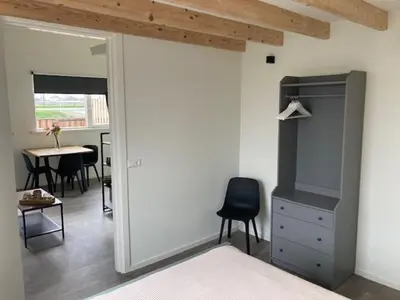 a bedroom with a bed and a chair and a table at Landzicht in Ter Aar