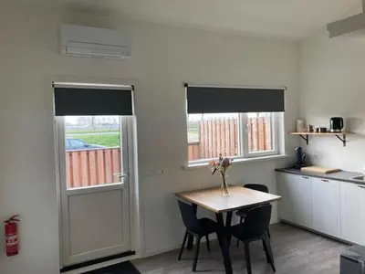 a kitchen with a table and chairs and two windows at Landzicht in Ter Aar