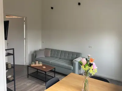 a living room with a couch and a table with flowers at Landzicht in Ter Aar