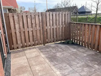 a wooden fence in a yard with a patio at Landzicht in Ter Aar