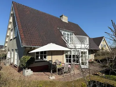 a house with an umbrella and a table and chairs at Villa Louise in Bergen aan Zee