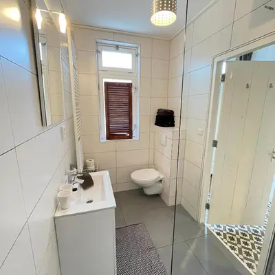 a white bathroom with a toilet and a sink at Kust 3 in Egmond aan Zee