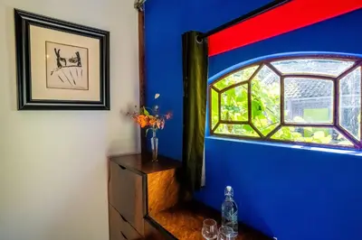 a blue room with a window and a wooden dresser at Reijgershof Art Deco Room with private bathroom in Amsterdam