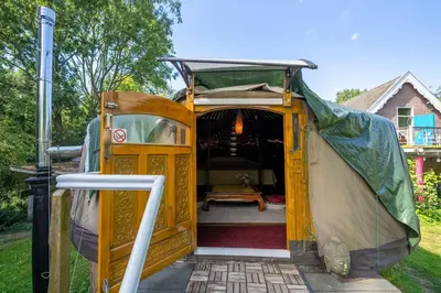 a camper van with the door open in a yard at Reijgershof - Yurt Experience with garden view in Amsterdam