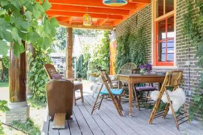 a porch with a wooden table and chairs on it at Reijgershof - Yurt Experience with garden view in Amsterdam