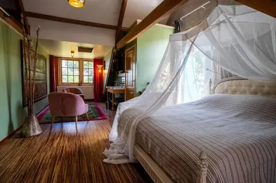 a bedroom with a canopy bed and a chair at Reijgershof - Bali Suite with private terrace in Amsterdam