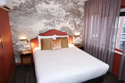 a bedroom with a white bed with a red headboard at Hotel Steeds aan Zee in Katwijk