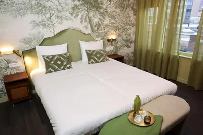 a bedroom with a large white bed with a table at Hotel Steeds aan Zee in Katwijk