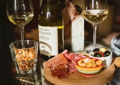 a bottle of wine and a plate of food and wine glasses at Hotel Steeds aan Zee in Katwijk