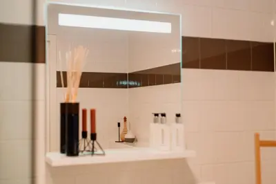 a bathroom with a mirror and a shelf with cosmetics at Hotel Steeds aan Zee in Katwijk