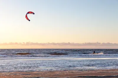 a person is flying a kite on the beach at Hotel Steeds aan Zee in Katwijk