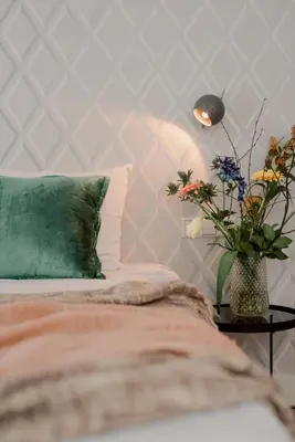 a bed with a pillow and a vase of flowers on a table at Hotel Steeds aan Zee in Katwijk