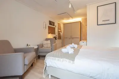 a bedroom with a bed and a couch and a chair at Guesthouse De Drukkerij in Zandvoort