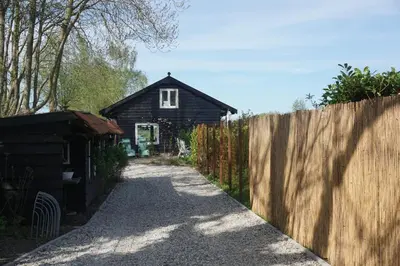 a small house with a fence next to a driveway at The Barn in Loosdrecht