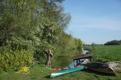 a group of boats sitting on the side of a river at The Barn in Loosdrecht
