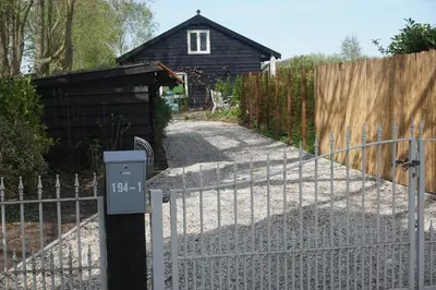 a fence and a gate with a house behind it at The Barn in Loosdrecht