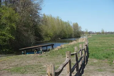 a house on a river next to a fence at The Barn in Loosdrecht