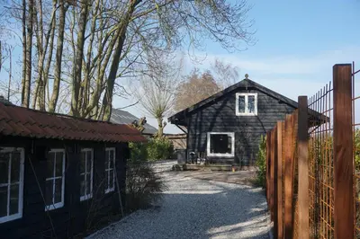 a black house with a fence in front of it at The Barn in Loosdrecht