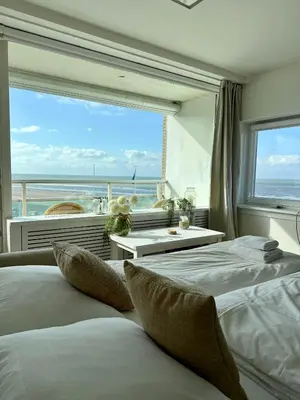 two beds in a room with a view of the ocean at Nicky's Seaview in Zandvoort