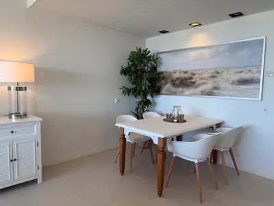 a dining room with a table and white chairs at Nicky's Seaview in Zandvoort