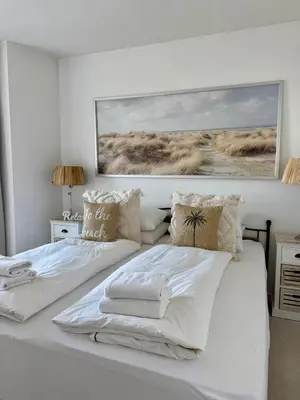 a bedroom with a white bed with a picture on the wall at Nicky's Seaview in Zandvoort