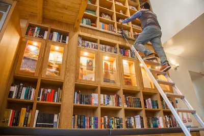 a person is climbing a ladder in a book shelf at Hotel Library Amsterdam in Amsterdam