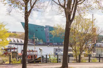 a boat is docked at a marina with trees at Hotel Library Amsterdam in Amsterdam