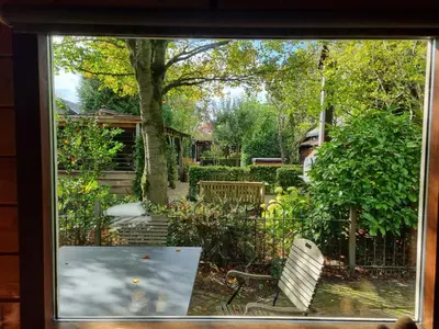 a window view of a garden with a table and chairs at B&B de Prieelhoeve in Almere