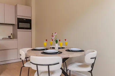 a dining room with a wooden table and white chairs at City & Trainhouse in Alkmaar