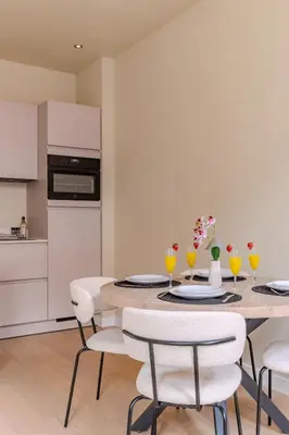 a kitchen with a table with white chairs and a kitchen with a stove at City & Trainhouse in Alkmaar