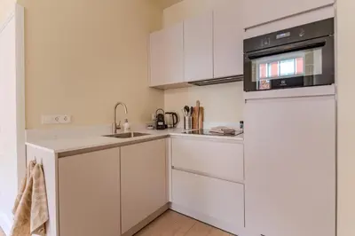 a white kitchen with white cabinets and a sink at City & Trainhouse in Alkmaar