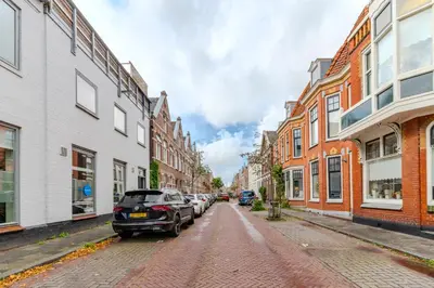 a city street with cars parked on a cobblestone street at City & Trainhouse in Alkmaar