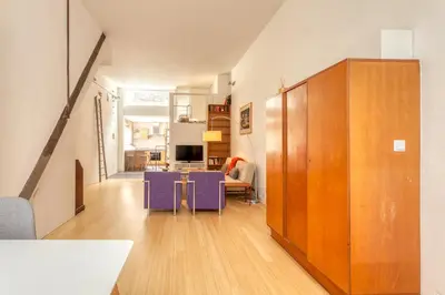 a living room with a large wooden cabinet and purple furniture at Voldersgracht Canal Home Haarlem in Haarlem
