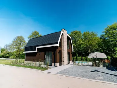 a building with a black roof and an umbrella at Stay with Private Pool & Hot Tub in Waarland