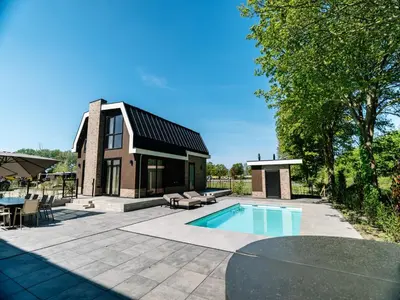 a home with a swimming pool and a house at Stay with Private Pool & Hot Tub in Waarland