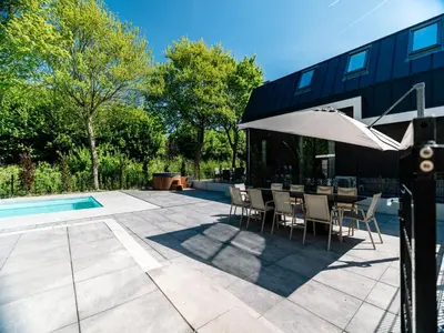 a patio with an umbrella and chairs next to a pool at Stay with Private Pool & Hot Tub in Waarland