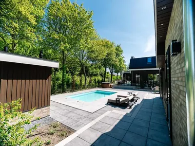 a swimming pool in a yard next to a building at Stay with Private Pool & Hot Tub in Waarland