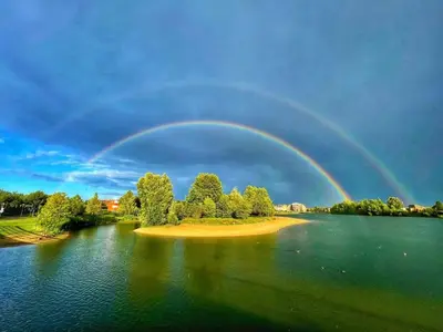 a rainbow over a lake with trees and houses at De Aanbouw van Foonloos - luxe studio vlakbij Utrecht in Houten