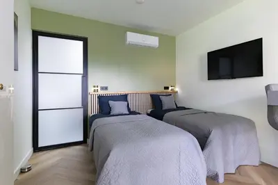 two beds in a room with a tv at De Aanbouw van Foonloos - luxe studio vlakbij Utrecht in Houten