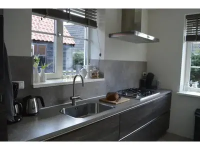 a kitchen with a sink and a stove and windows at Waddengoud in Ons Belang