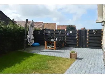 a patio with a table and an umbrella in a backyard at Waddengoud in Ons Belang