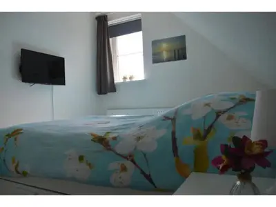 a bedroom with a bed with a blanket with flowers on it at Waddengoud in Ons Belang