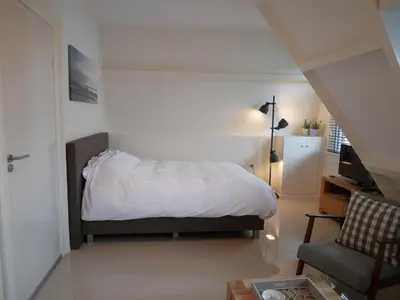 a bedroom with a bed and a chair at Casa Del Cisne in Zandvoort