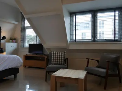 a bedroom with a bed and two chairs and a tv at Casa Del Cisne in Zandvoort