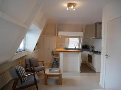 a small kitchen with white cabinets and a table at Casa Del Cisne in Zandvoort