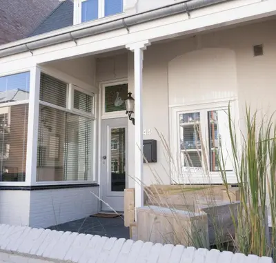 a white house with a door and a window at Casa Del Cisne in Zandvoort