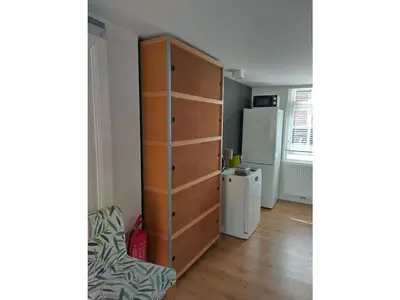 a room with a chest of drawers and a refrigerator at Centraal aan Zee in Egmond aan Zee