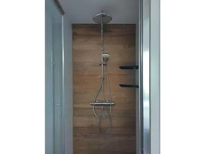 a shower in a bathroom with a wooden wall at Centraal aan Zee in Egmond aan Zee