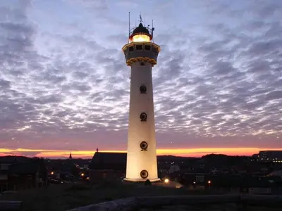 a lighthouse with a light on top at sunset at Centraal aan Zee in Egmond aan Zee